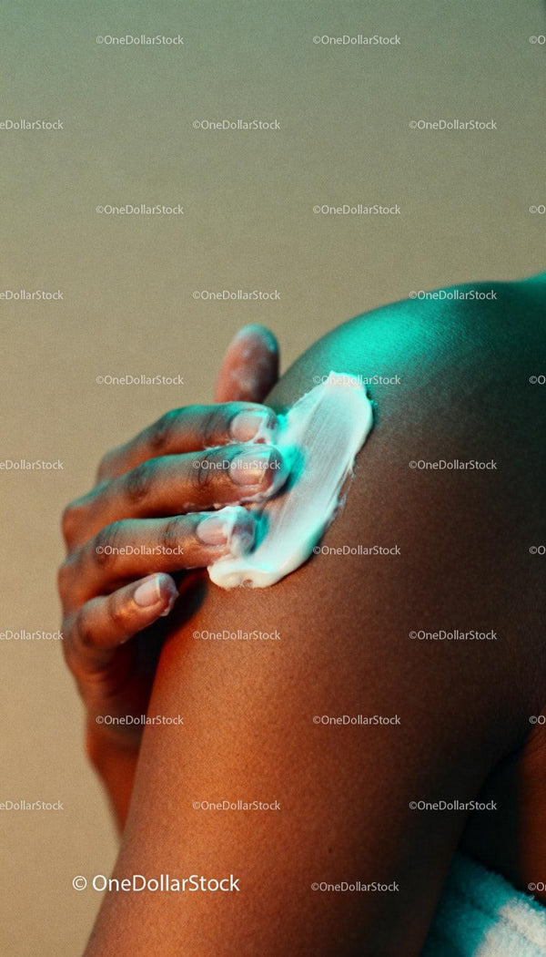 Close-up of hand moisturizing smooth skin on shoulder