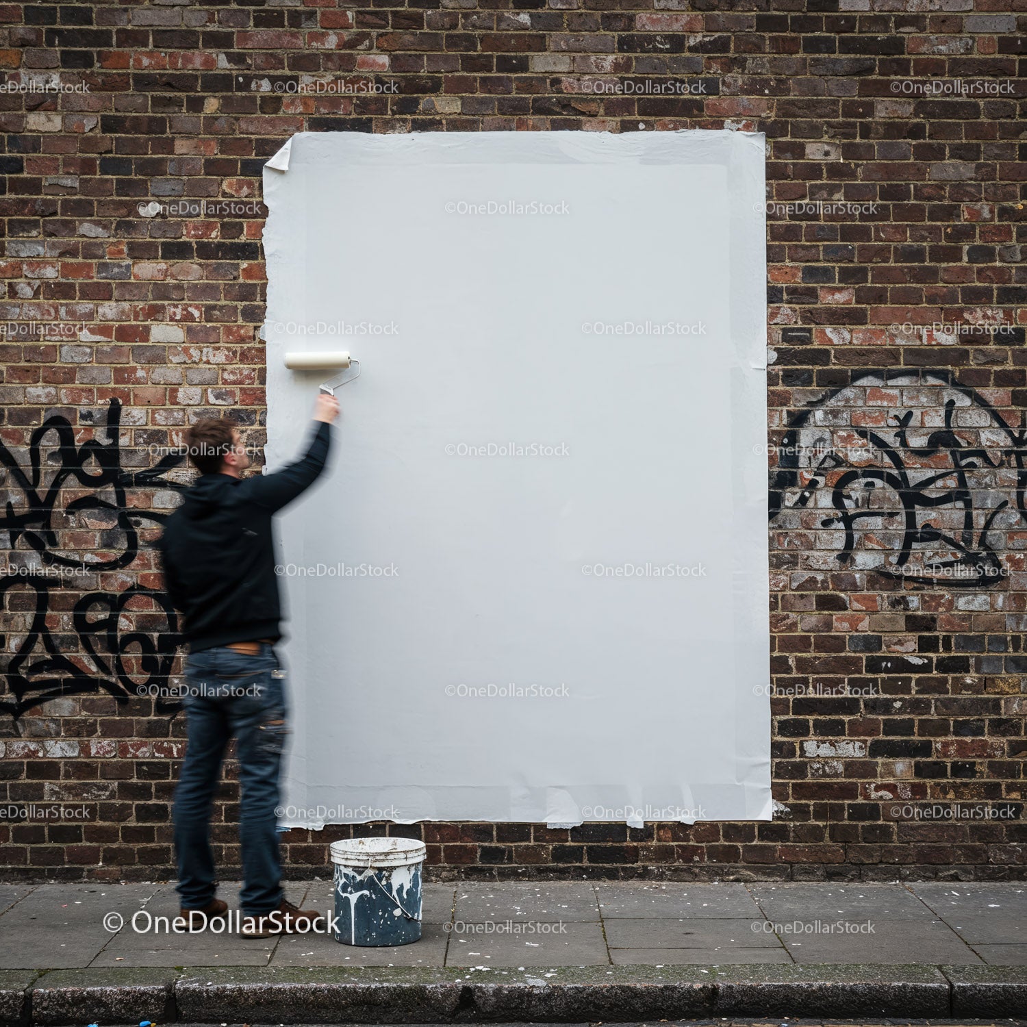 Mężczyzna malujący graffiti na miejskiej ścianie z cegły