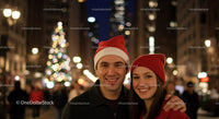 Couple wearing festive hats smiling in city at night