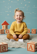 Smiling toddler in yellow sweater playing with wooden blocks