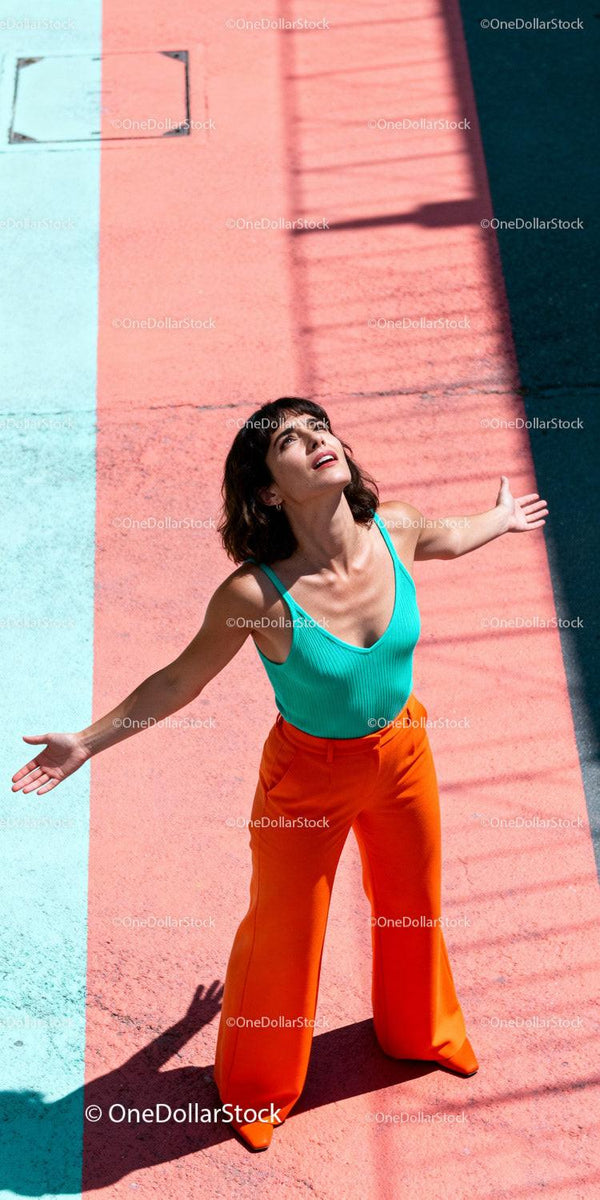 Confident woman standing with open arms under sunlight