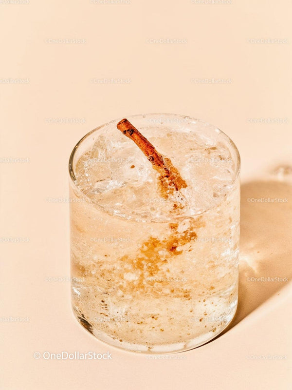 Refreshing cocktail with cinnamon stick on light background