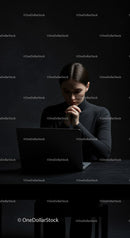 Thoughtful Woman at Laptop in Dark Modern Workspace