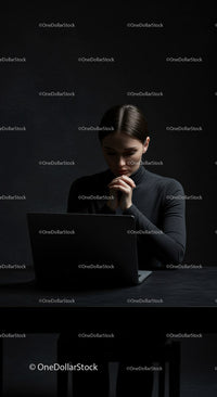 Thoughtful Woman at Laptop in Dark Modern Workspace