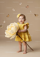 Toddler girl in yellow dress holding oversized flower