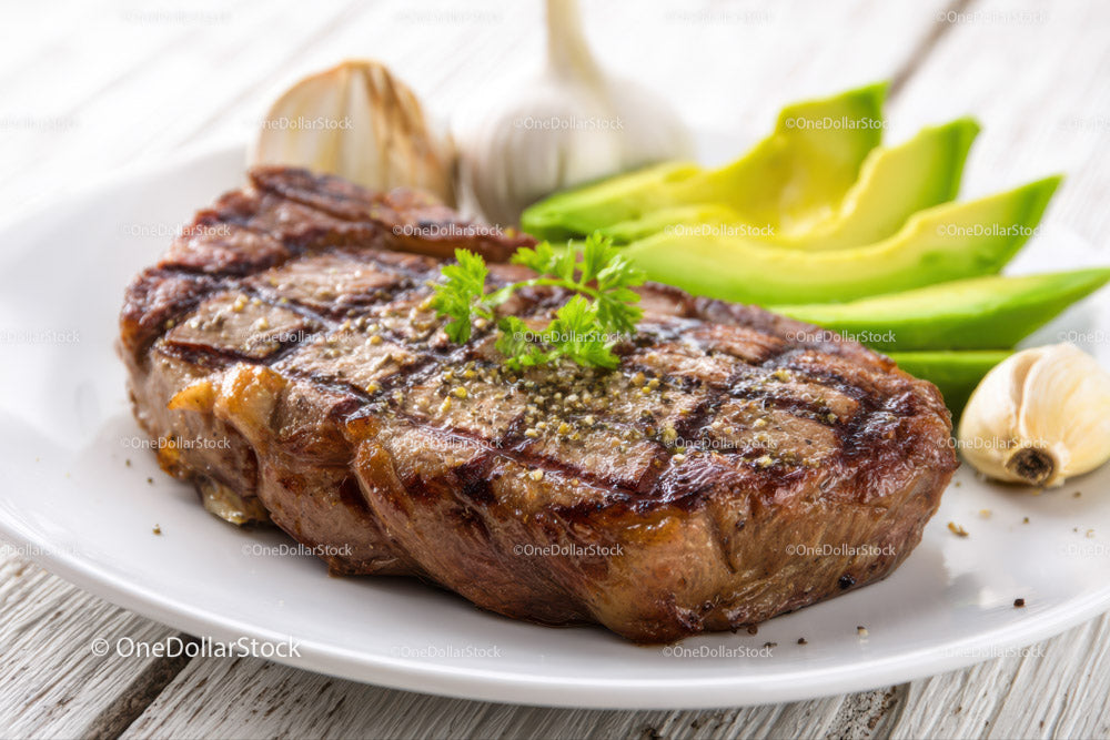 Juicy Grilled Steak with Fresh Avocado and Garlic on Rustic Board