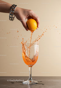 Hand squeezing fresh orange juice into wine glass