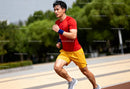 Determined man running outdoors in bright athletic wear