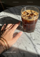 Hand Reaching for Glass of Iced Coffee on Marble Table