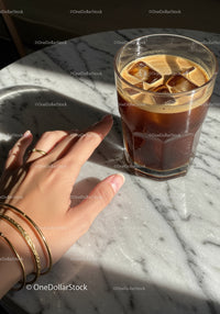 Hand Reaching for Glass of Iced Coffee on Marble Table