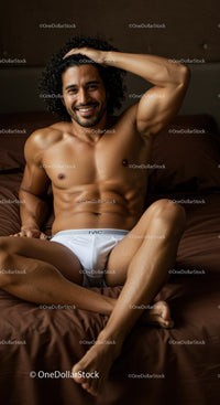 Relaxed muscular man smiling on brown bed in white briefs