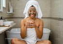 Happy Woman with Facial Mud Mask Relaxing in Bathroom
