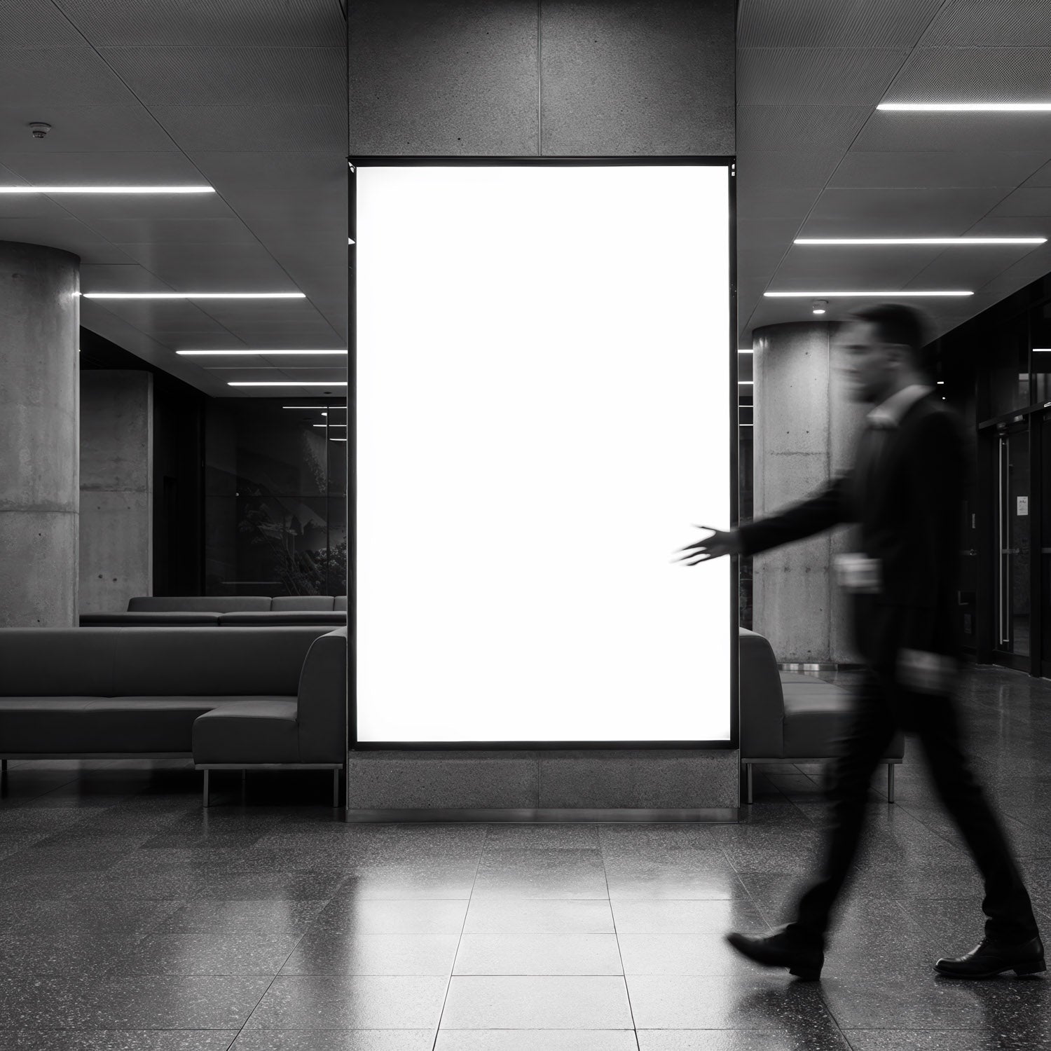 Blurred businessman walking past illuminated blank billboard