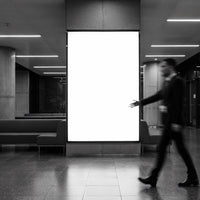 Blurred businessman walking past illuminated blank billboard