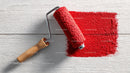 Red Paint Roller Spreading Bright Red Color on Wooden Surface