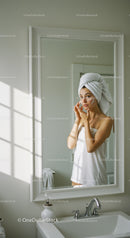 Woman Applying Facial Cream in Bathroom Mirror During Skincare Routine