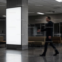 Blurred man walking past blank illuminated billboard indoors