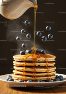 Stack of fluffy pancakes topped with syrup and blueberries