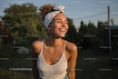 Joyful Young Woman Smiling Outdoors Under Sunny Sky