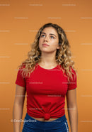 Young woman in red shirt looking thoughtfully upward