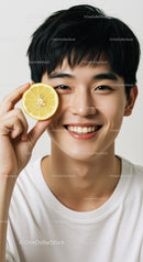 Young Man Playfully Holding Lemon Slice to Eye With Bright Smile