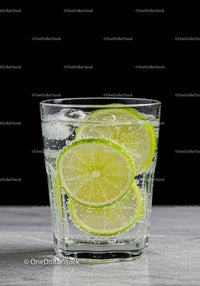 Refreshing sparkling water with lime slices on marble