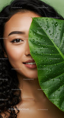 Elegant Woman with Curly Hair and Large Green Leaf Close-Up