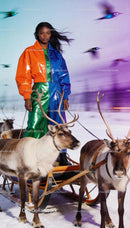 Woman in colorful outfit standing with reindeer sled
