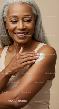 Smiling Elderly Woman with Gray Hair Applying Lotion to Shoulder