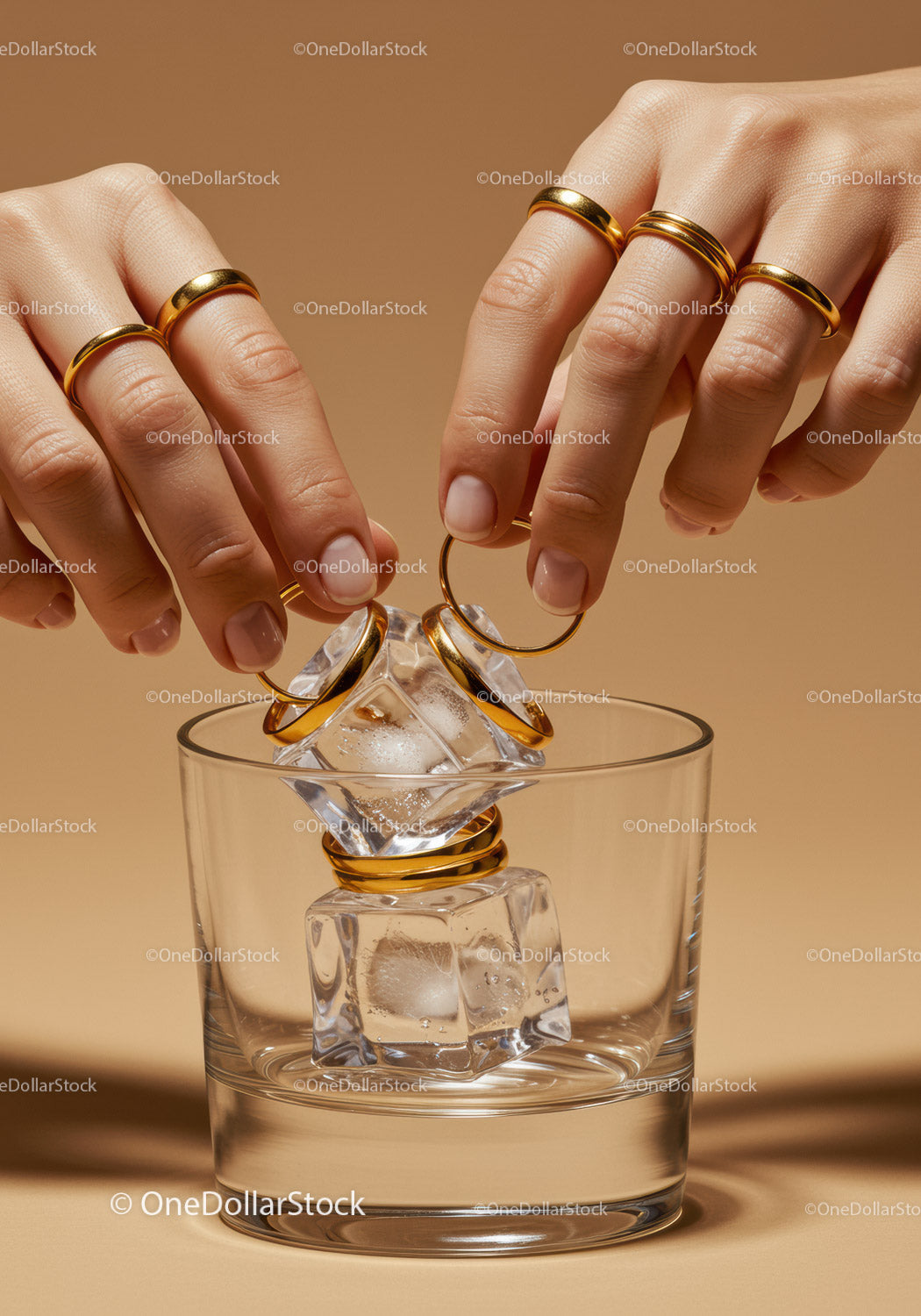 Hands Adorning Ice Cubes with Gold Rings in Glass