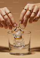 Hands Adorning Ice Cubes with Gold Rings in Glass