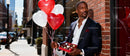 Elegant man holding chocolates and heart balloons outdoors