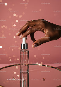 Hand Holding Serum Dropper with Cosmetic Bottle on Pink Background