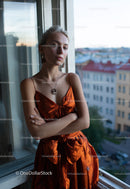 Elegant Woman in Orange Satin Dress by Window with City View