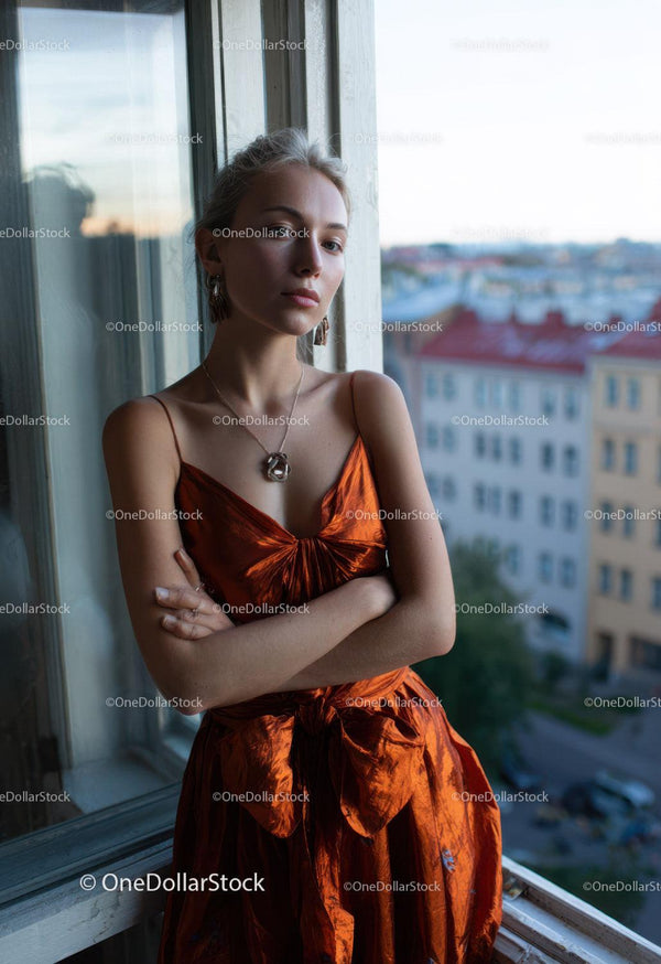 Elegant Woman in Orange Satin Dress by Window with City View