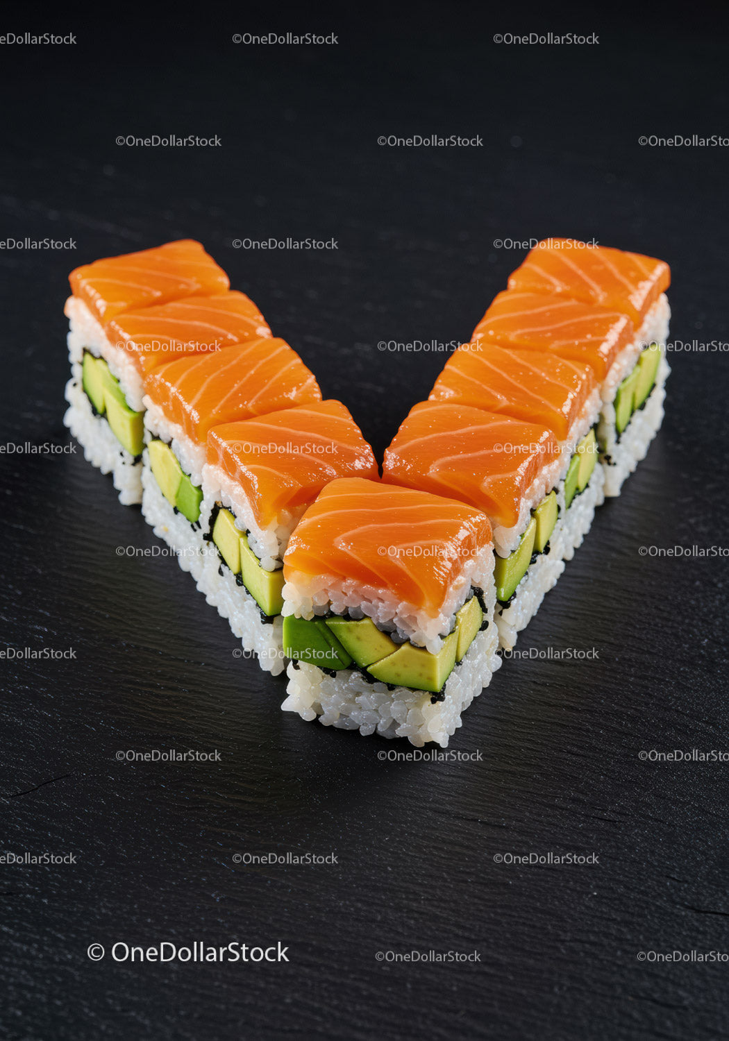 Fresh salmon avocado sushi arranged in V shape on black slate