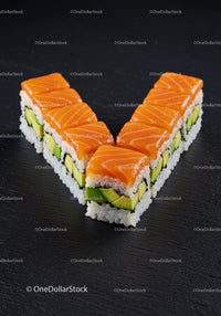 Fresh salmon avocado sushi arranged in V shape on black slate
