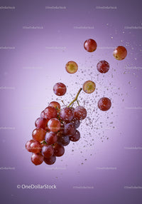 Fresh red grapes splashing in water on purple background