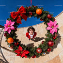 Young woman in Santa dress framed by large Christmas wreath