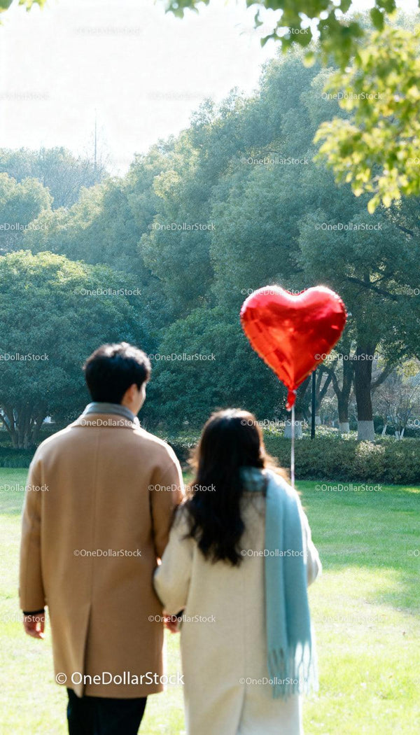 Couple Walking in Park Holding Heart Shaped Balloon