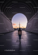 Woman Walking Through Modern Cityscape Under Twilight Sky