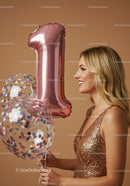 Smiling woman holding number one balloons for celebration