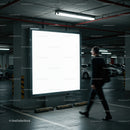 Man walking past illuminated blank billboard in parking garage