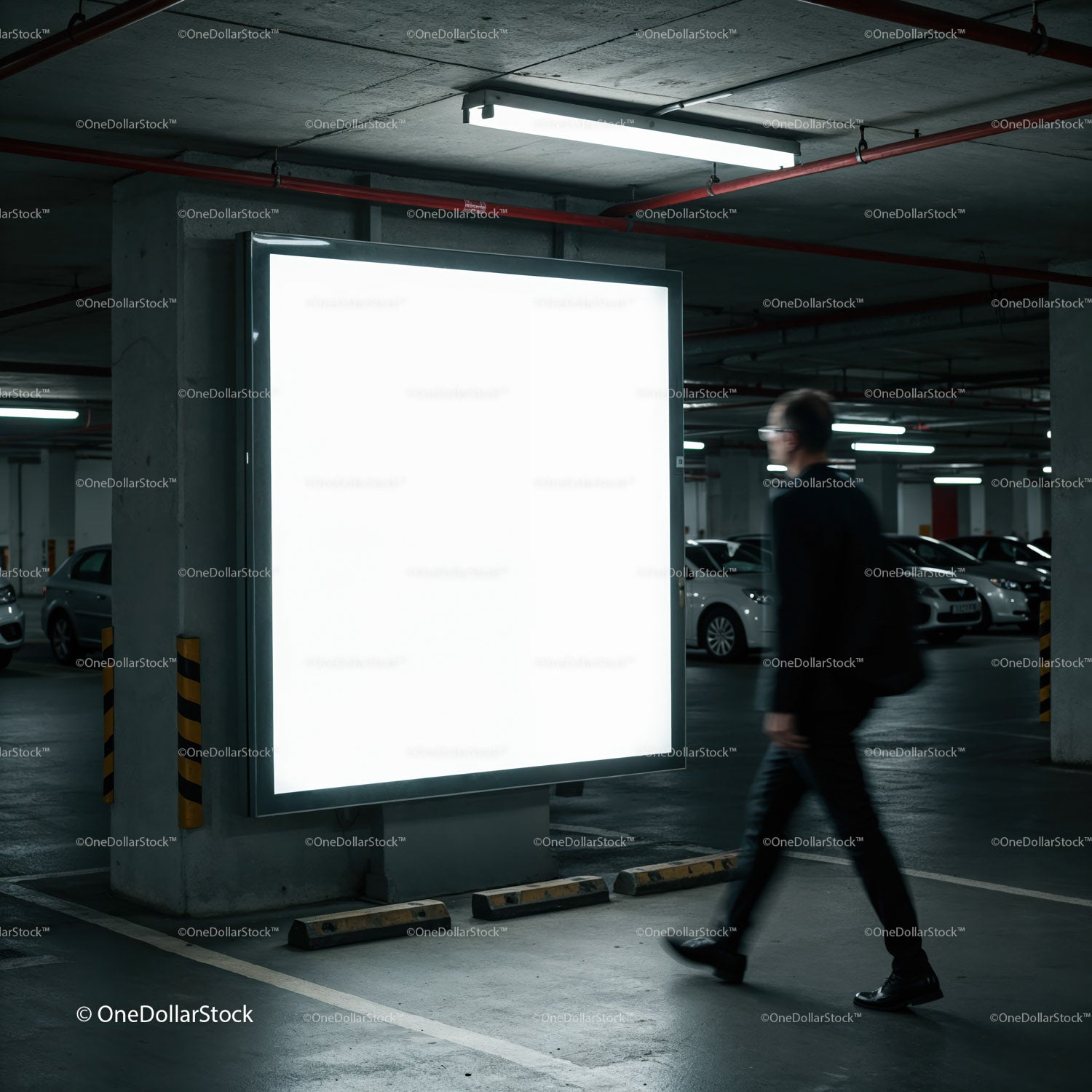 Mężczyzna przechodzi obok oświetlonego, pustego billboardu w garażu parkingowym