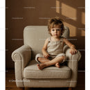 Toddler sitting calmly on a cozy armchair indoors