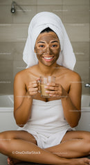 Joyful Woman in Spa Towel with Green Facial Mask Holding Glass of Tea