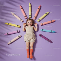 Smiling toddler lying surrounded by giant colorful crayons
