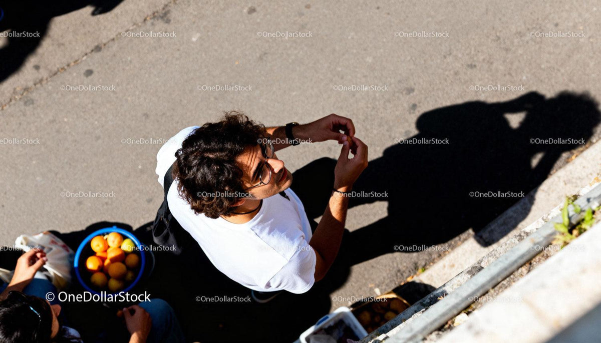 Young man peeling fruit while standing on street