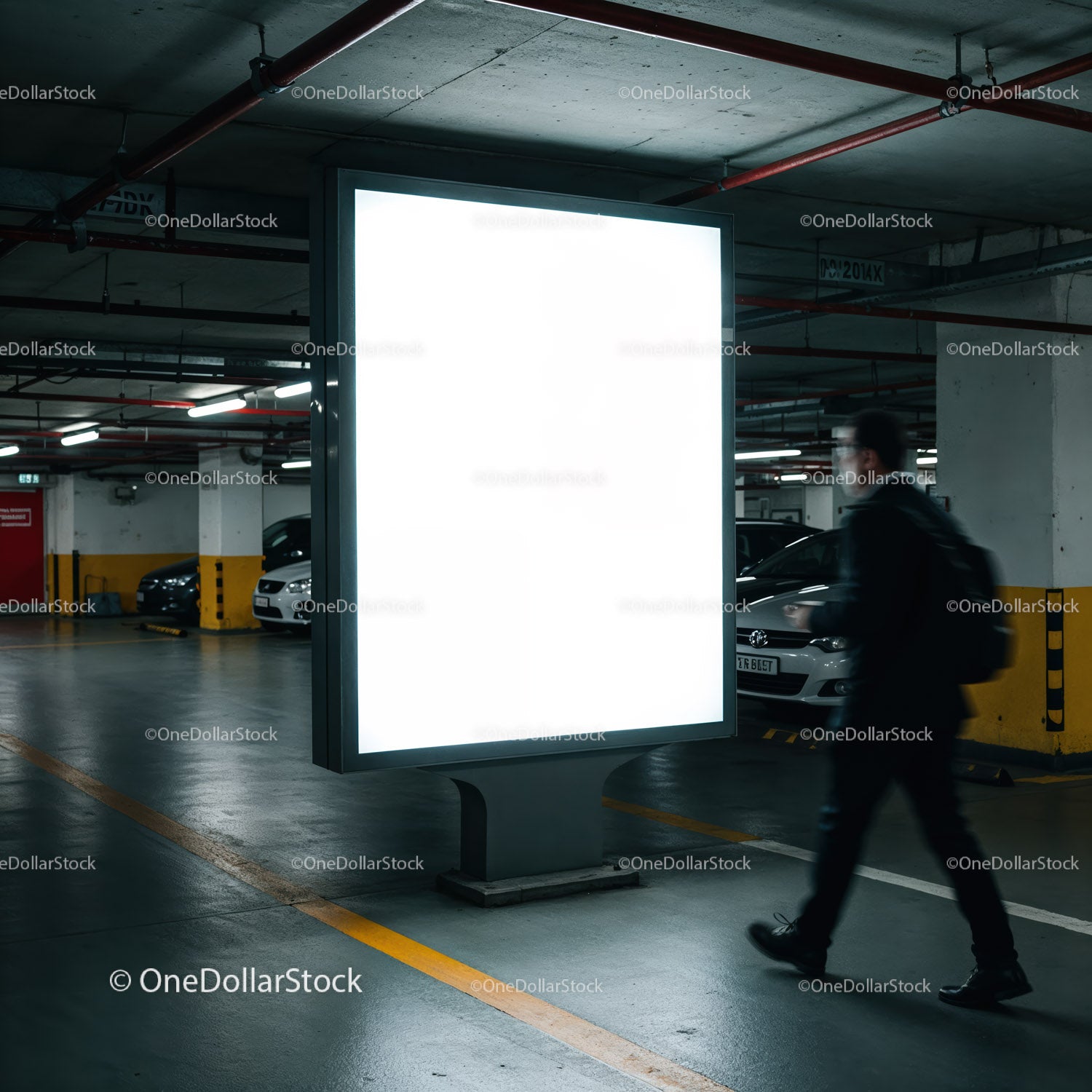 Mężczyzna przechodzący obok oświetlonego billboardu w garażu podziemnym