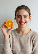 Joyful Woman Holding a Bright Orange Slice for Healthy Living Concept